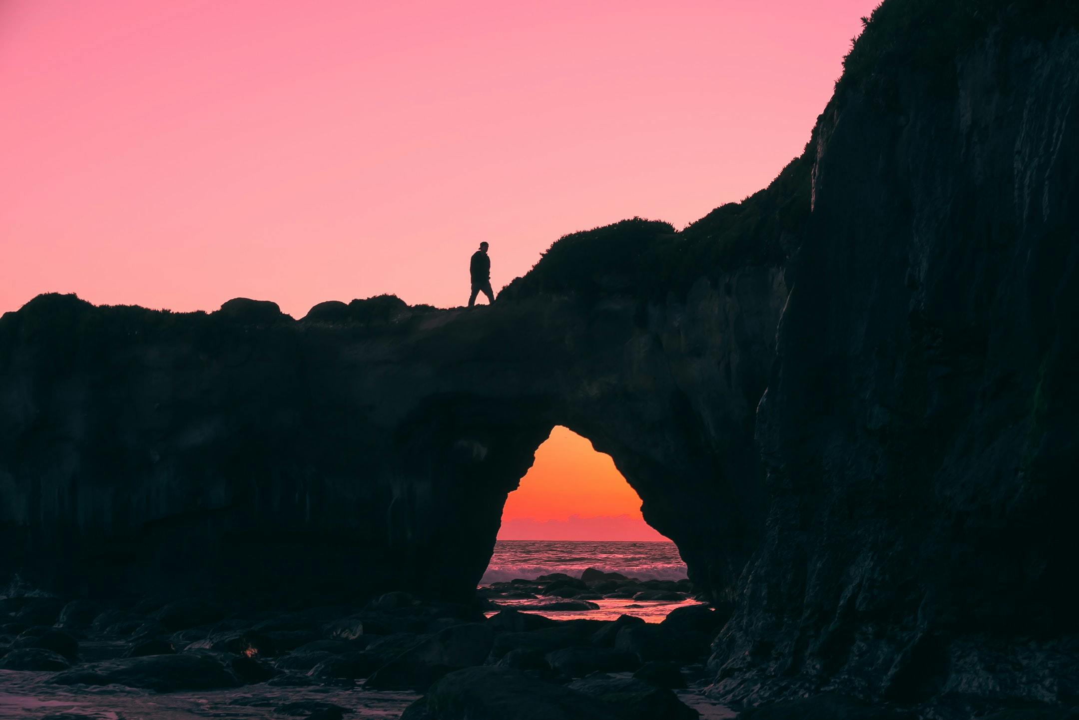 Photo by Jeff Nissen of silhouette of someone walking on cliff edge during sunset